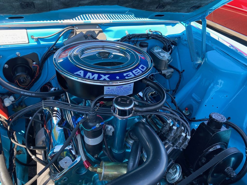 1969 AMX, a two-seat GT sport coupe made by American Motors Corporation (AMC). This muscle car is driven and has over 166,000 miles on the odometer because trailers are for boats! It has the 390 "Go Package" that included the 390 cu in (6.4 L) high-compression 4-bbl 315 hp (235 kW; 319 PS) V8 engine, racing stripes, power front disk brakes, Twin-Grip rear differential, E70x14 performance tires, and other high-performance components. This car has the factory original "Big Bad Blue" paint. An option that included painted bumpers and rear bumper guards. These pictures were taken during the American Motors Owners Association (AMO) annual convention in June 2024, organized by the Potomac Ramblers Club. Most events were held at the Keystone Truck and Tractor Museum in Petersburg, Virginia.