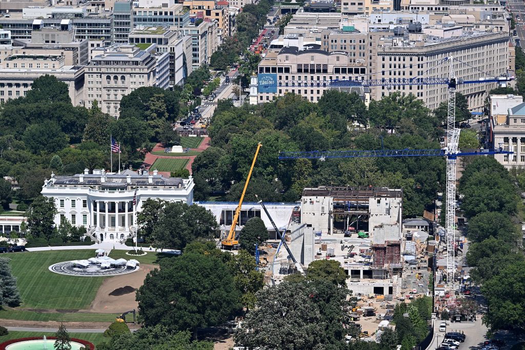 On the right is the ongoing construction of the White House Ballroom, which replaces the East Wing. Towards the back right, portions of the new building reach two stories above ground. Directly in front of the White House is construction of a new helipad to support the latest version of Marine One for the president. The White House is directly behind it. 1600 Pennsylvania Ave NW, Washington, DC 20500. September 9, 2026.