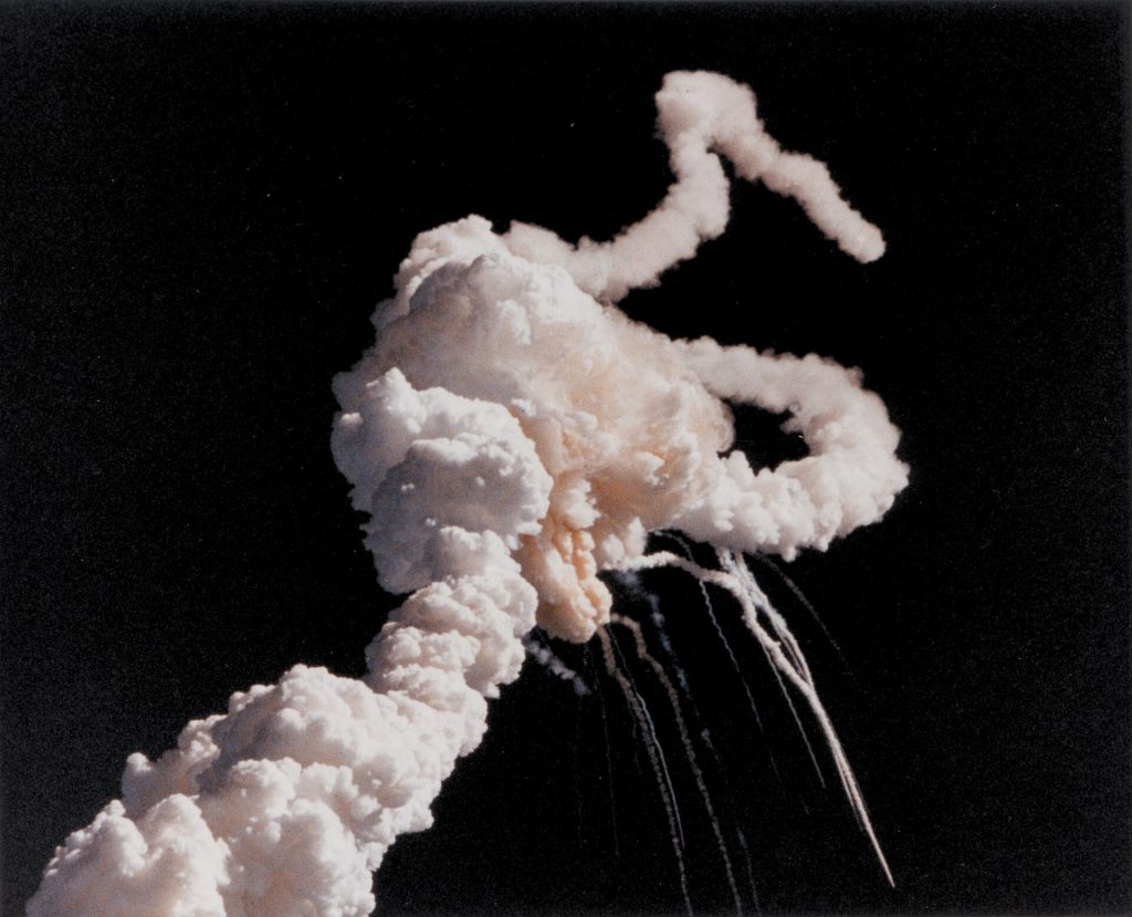 Short Description: Space Shuttle Challenger explodes shortly after take-off. Full Description: On January 28, 1986, the Challenger space shuttle and her seven-member crew were lost when a ruptured O-ring in the right solid rocket booster caused an explosion soon after launch. This photograph, taken a few seconds after the accident, shows the main engines and solid rocket booster exhaust plumes entwined around a ball of gas from the external tank. Because shuttle launches had become almost routine after 24 successful missions, those watching the shuttle launch in person and on television found the sight of the explosion especially shocking and difficult to believe until NASA confirmed the accident. Image # : 86-HC-220 Title: Exhaust Trail of STS-51-L