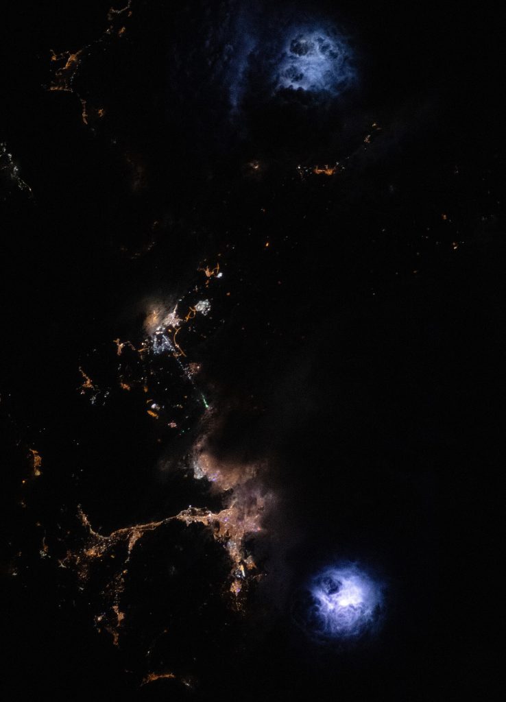 An astronaut aboard the International Space Station took this photograph of a thunderstorm at night over western Türkiye. The image highlights two distinct lightning flash areas, one southeast of the city of İzmir and the other north of Aliağa. Using a camera’s time-lapse function and the proper shutter speed, astronauts can capture photos of the bright flashes amidst the clouds while simultaneously documenting nearby nighttime lights from cities and highways. The image’s high spatial resolution, combined with the temporary illumination of the lightning flash, reveal the cloud textures from above—a unique attribute of astronaut photography of Earth at night. The dark and light patches within the cumulonimbus clouds expose the strong updrafts present in storm cells. In addition to lightning, the image captures the municipal lights from the cities of İzmir, Yelki, and Aliağa bordering the Gulf of İzmir. Storm clouds obscure some of the urban lights toward the eastern side of the gulf. Remote sensing of nighttime storms has been the focus of several scientific projects aboard the space station. Astronaut imagery has extended our understanding of atmospheric phenomena associated with lightning, including sprites and blue jets. In addition to crew photography of Earth, robotic sensors aboard the station, such as the European Space Agency’s Atmosphere-Space Interactions Monitor (ASIM), observe these atmospheric phenomena and convective storms. Scientists have also used the data collected by the Lightning Imaging Sensor (LIS) to map lightning strikes and gain insight into lightning dynamics across the planet during both daytime and nighttime storms.