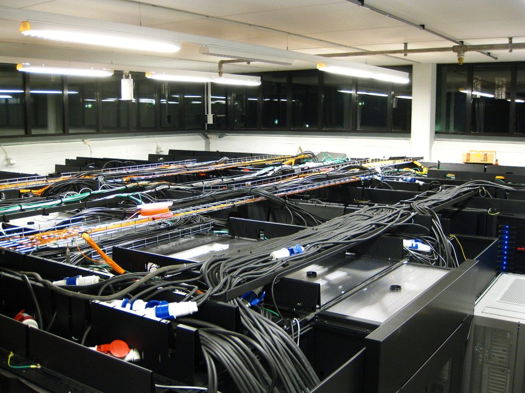 Server room at Royal Institute of Technology Parallel Computer Center.Thick black cables are power, orange and yellow cables are fiberoptics, green and grey cables are ethernet. The pipes in the cieling are intert-gas extinguisher.
