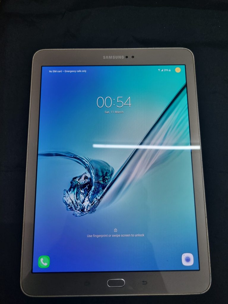 A Samsung Galaxy Tab S2 tablet photographed from the front, with the screen turned on and displaying the Android lock screen. The image shows the time, date, battery status, and standard lock screen icons, along with the physical home button below the display. The device is manufactured by Samsung Electronics and runs the Android operating system. Image taken from India.