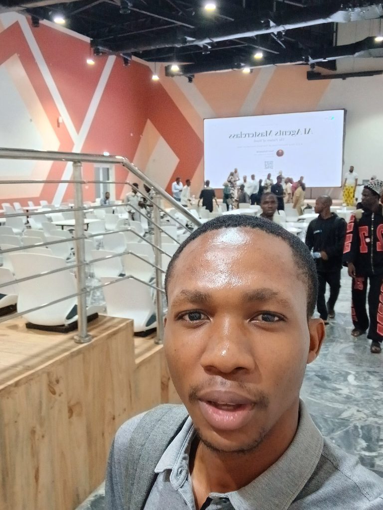 A portrait selfie showing an attendee inside the auditorium at the Ilorin Innovation Hub (9a Ahmadu Bello Way, Ilorin, Kwara State, Nigeria) during the "AI Agents Masterclass: The Future of Work" presentation.
