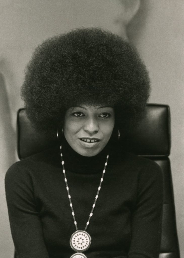 Angela Davis, half-length portrait. The original has "x" markings that indicate the photographer's or editor's selection of a photo for printing. Call Number: LOT 14191-D, no. 37 Cropped from File:Angela Davis in a half-length portrait by Bernard Gotfryd.jpg to better resemble how it would have been printed after being marked up.